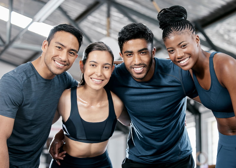 A group of men and women in activewear smiling at a camera.